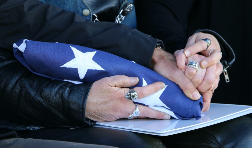 Sister's holding hands and folded American flag given them at their father's funeral.